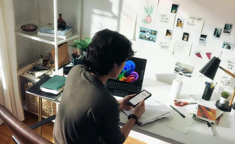 Iemand aan het werk achter een laptop en telefoon